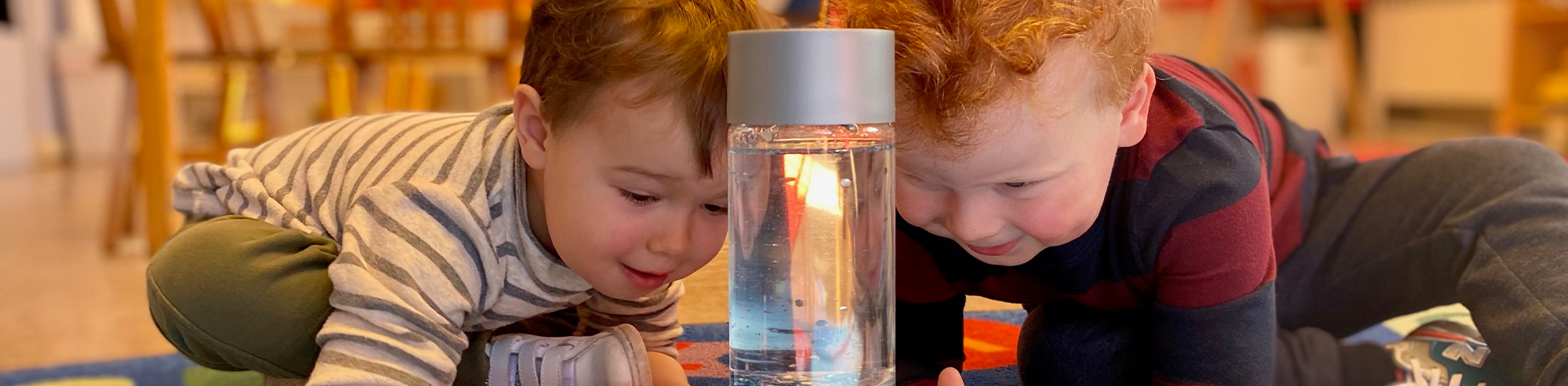 two young children looking at glass jar