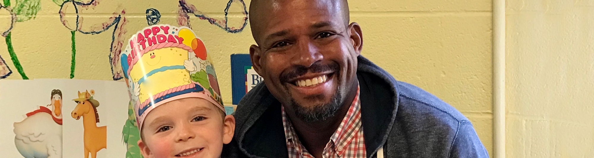 staff member with a boy wearing a birthday hat