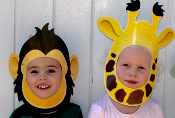 two children, one with a monkey mask and another with a giraffe mask 