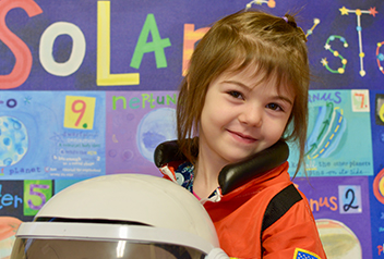 girl in astronaut suit holding a helmet