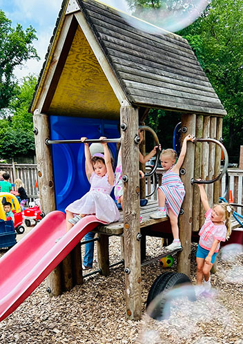 Young children playing outside on the slide